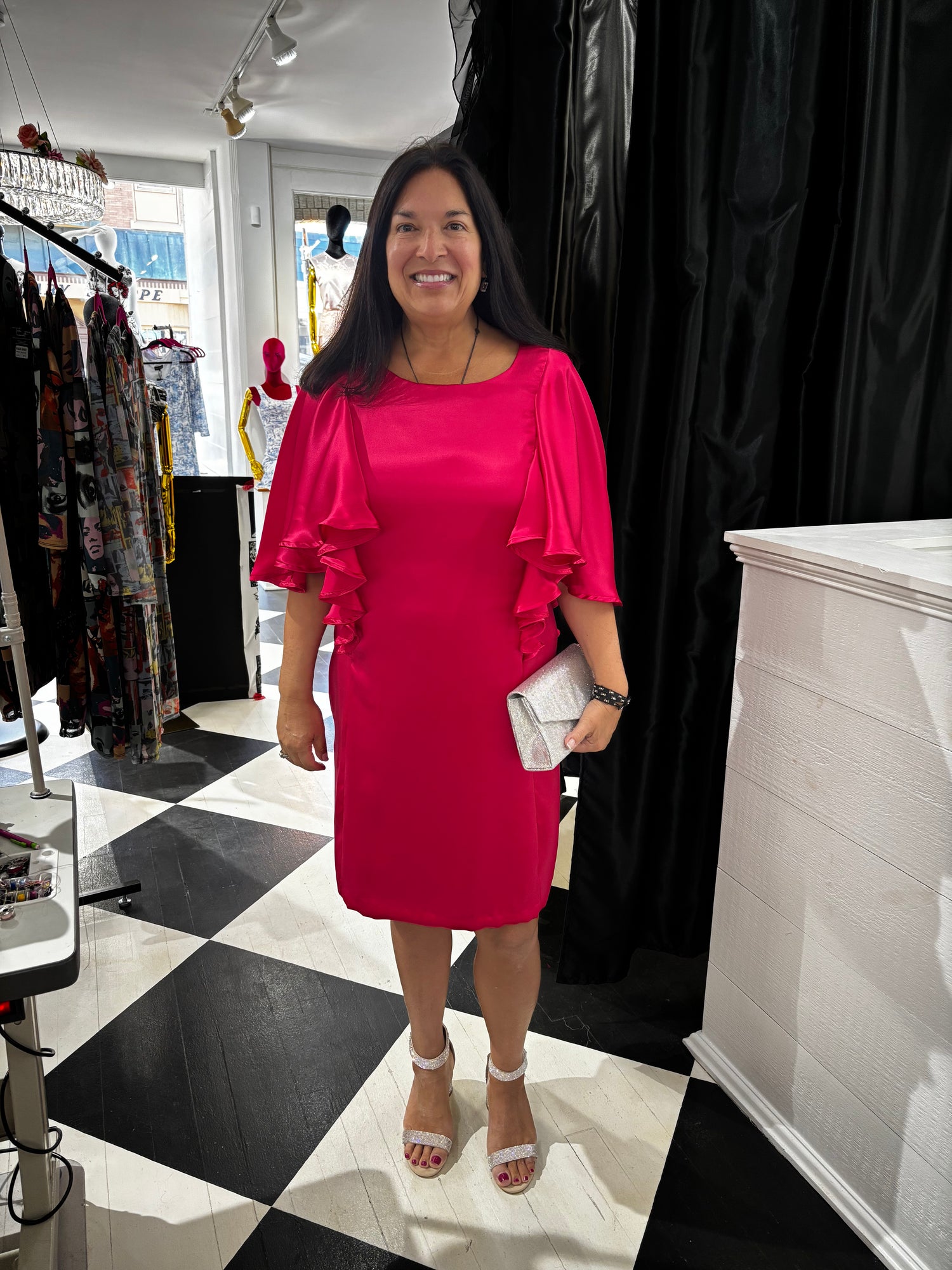 Woman in a bright pink dress standing in a store with a checkered floor.