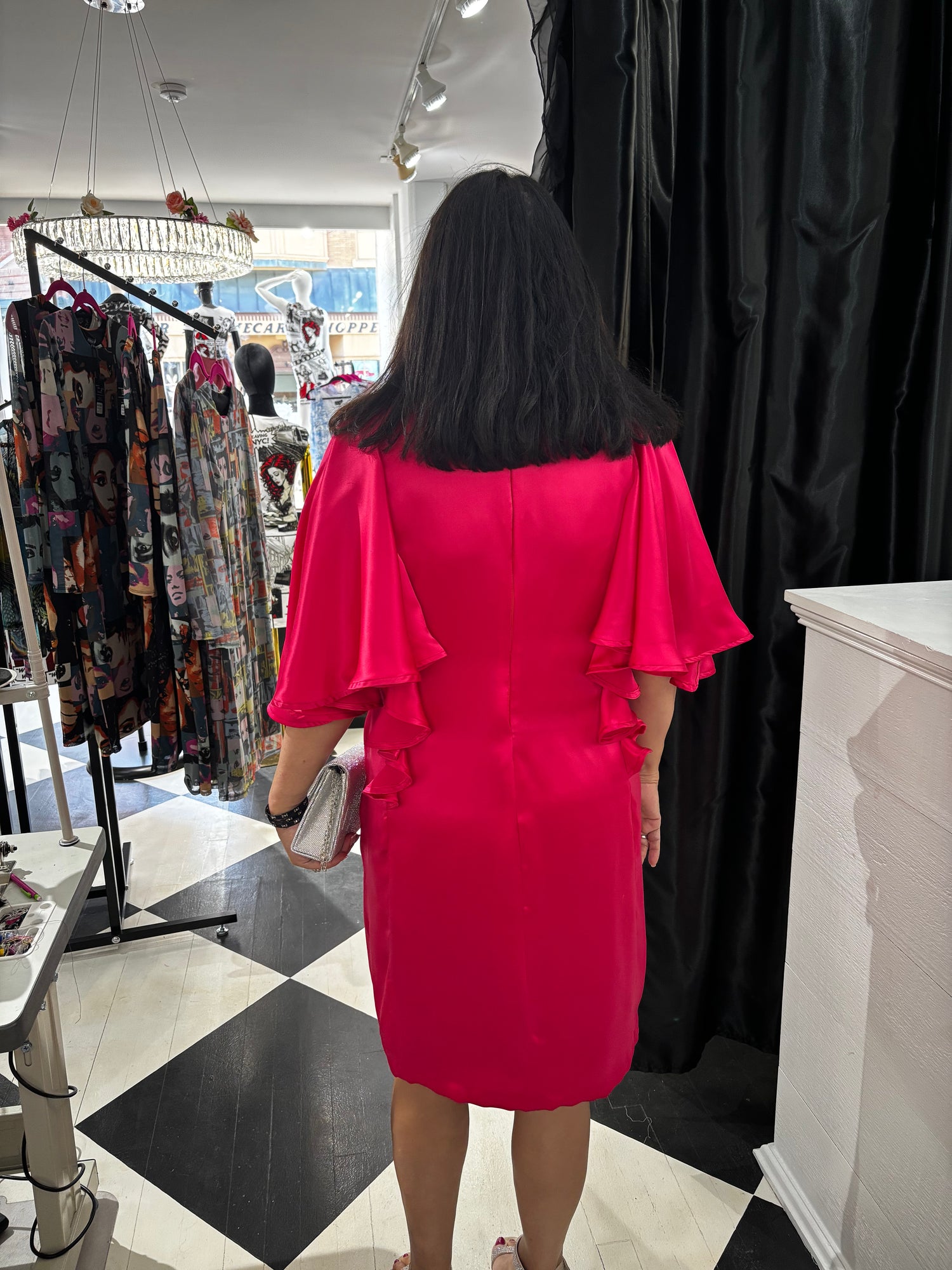 Woman wearing a bright pink dress in a clothing store.